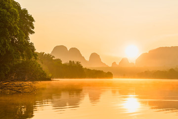 Stunning beautiful nature scenic misty landscape of lake in the morning with reflection of nature on water at sunrise time, Ban Nong Thale Krabi province, Rural fog scenery Thailand, Asia