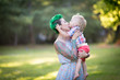 A portrait of Caucasian young woman with green hair and tattoo holding a blond toddler boy in her hands. Hugging, Mother's day concept