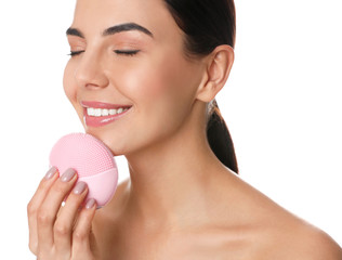 Poster - Young woman using facial cleansing brush on white background. Washing accessory