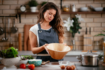 Wall Mural - Young woman in kitchen. Beautiful woman baking. 