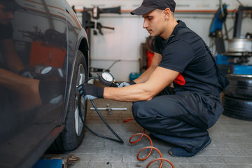 Wall Mural - Auto mechanic checks the tire pressure in service