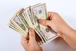 © Yaroslav - Woman's hands counting dollar bills on a white background.