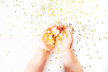 Children's Hands With Gold Spangles On A White Background
