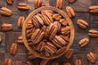 pecan nuts peeled in wooden bowl, top view.