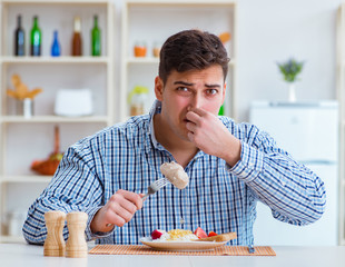 Wall Mural - Man eating tasteless food at home for lunch