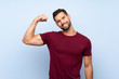 © luismolinero - Handsome man over isolated blue background doing strong gesture