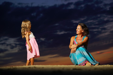 mother and daughter at sea with sunset