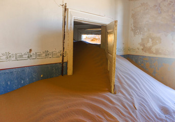 Abandoned and forgotten building and room left by people and being taken over by encroaching sandstorm, Kolmanskop ghost town, Namib Desert