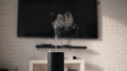 air humidifier in a modern cozy smart house in front of plasma tv. vapor coming from electric air hu