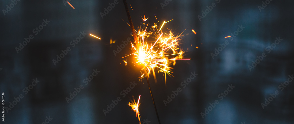 Sparklers for Christmas and New Year close-up in the form of a banner and on a blue background - obrazy, fototapety, plakaty 