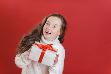 Happy excited girl child holding christmas gift box.