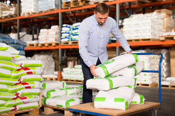 Man choosing compost soil in plastic bags in hypermarket