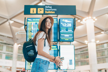 young tourist in a hat with a backpack walks past the placard at the airport