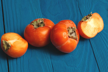 Wall Mural - persimmon fruit on a blue wooden background