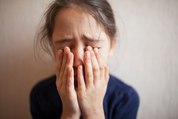 Little girl covers her face with hands and cries