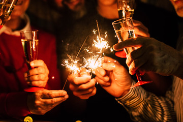 close up of people celebrate new year eve with sparklers and sparkling wine - nightlife concept - bi