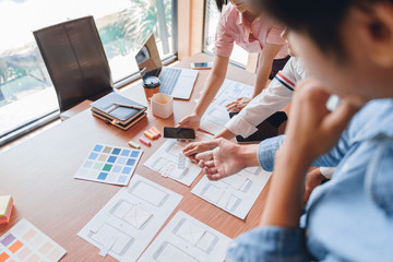 mobile apps developers team designing, discussing together on a user interface wireframe screens lay