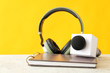 Microphone, headphones and notebook on table against color background
