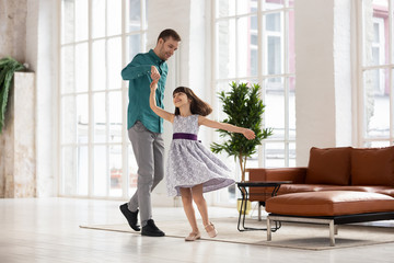 Canvas Print - Happy loving father leading in dance holding daughter hand up.