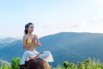 Asian woman doing exercise yoga. sitting in Sukhasana exercise, Easy Seat pose pose. Amazing yoga landscape in beautiful and enjoying mountain view with morning, concept for exercising, health care.