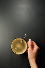 Wall Mural - A cup of coffee in hand, black background. View from above