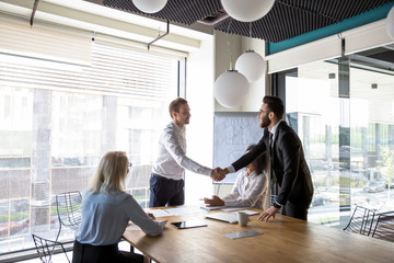 Canvas Print - Multiracial male business partners handshake greeting at meeting