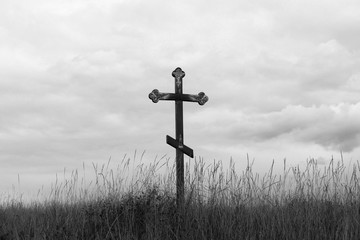 Black-and-white photo with wooden cross on sky background