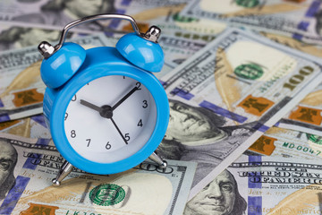 money and alarm clock on a blue background, copy spaсe	