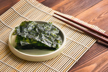 Crispy Nori Sheets And Bamboo Mat On Wood Table. 