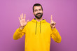 © luismolinero - Handsome man with yellow sweatshirt counting six with fingers
