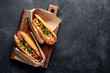 © александр таланцев - french hot dogs from the store  packaged in paper, baked with cheese and mustard on a stone background with copy space for your text