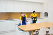 © xartproduction - professional cleaning service. Two women in working uniform, in aprons, divide the cleaning of the kitchen of a private house, cottage. washing the refrigerator, tap, sink. Wash floor.