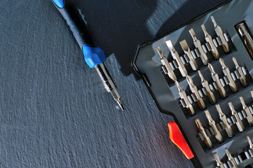 small screwdriver with a set of bits on a dark background. top view.