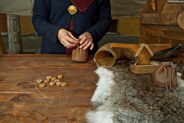 Girl with blue eyes wonders on the runes. Blonde in a Viking costume at the Middle Ages Festival. Authentic clothing and lifestyle of the tribes of the northern peoples. Fur on a wooden table.