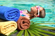 Young girl in the swimming pool. Beauty spa water. Towels, palm leaf on the water.
