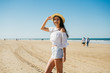 © mnelen.com - joyful girl on the beach is standing in shorts and a blouse holding her hat on her hand and smiling cute against the background of the oceans