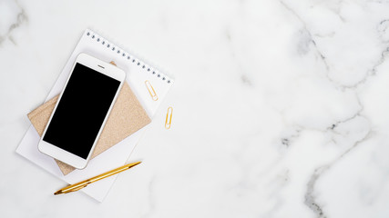 Wall Mural - Set of office supplies and smartphone with blank screen mockup on white marble background. Flat lay, top view, copy space. Home office desk table concept.
