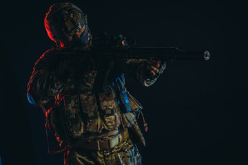 Wall Mural - brave military man shooting weapon and wearing uniform, serving in military forces, aimed gun at side, UV rays on body