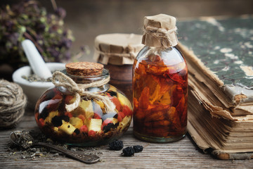 Wall Mural - Bottles of essential oil or infusion, mortar and old book. Herbal medicine.