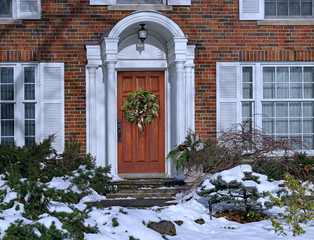 Wall Mural - Front door of snow covered house with Christmas wreath.