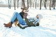 © vitaliymateha - Young happy woman in woolen hat and long warm scarf playing with her pet in snowly winter park at frozzy sunny day. Happy time together, cute dog Welsh Corgi Pembroke, winter holodays.