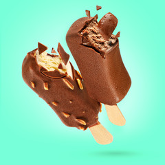 Two bitten chocolate ice creams popsicle on green background