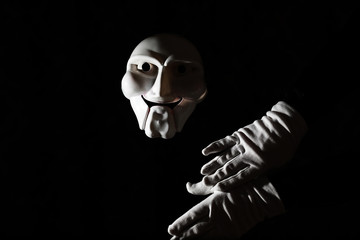 White scary mask on a black background with whites hand.