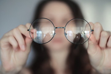 The concept of poor vision. Hold a contact lens and glasses in hand. A poster for advertising glasses and lenses.