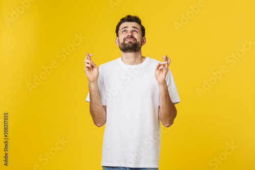 Fotomural Young man making a wish isolated on yellow background