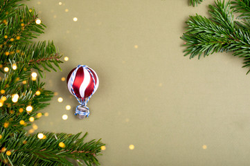 The air-balloon made of Christmas tree decoration ball. Pine tree branches on green background with place for the text.