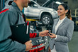 © Valerii Apetroaiei - Beautiful businesswoman and auto service mechanic are discussing the work and giving keys. Car repair and maintenance.