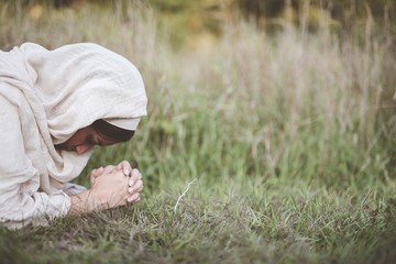 Poster - Shallow focus shot of a female down on the ground praying while wearing a biblical robe