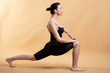 © Сергей Уланов - Side view portrait of beautiful young woman wearing white tank top working out against orange background, doing stretching.