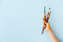 Hand Of Artist With Brushes On Color Background